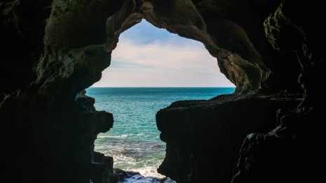 Touristes contemplant l'ouverture en forme de carte de l'Afrique à l'intérieur des Grottes d'Hercule