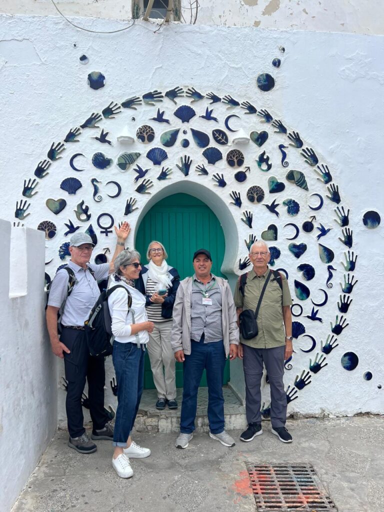 Guide and four guests in front of a blue-tile arch in Asilah