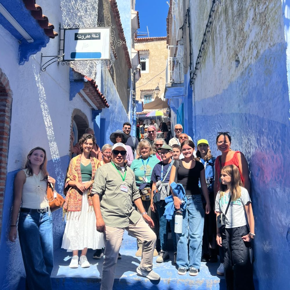 Touristes et guide local naviguant sur les célèbres marches bleues de la médina de Chefchaouen.