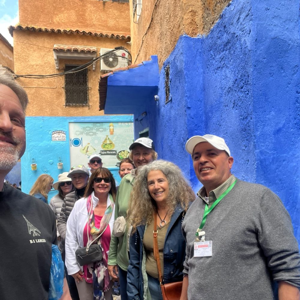 Travelers and their private local guide taking a group selfie in front of a traditional Moroccan restaurant in Chefchaouen.